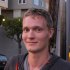 Rune Soerensen Dotnet Language Owner A young man with short blond hair wearing a gray hoodie stands outdoors in a residential area, with buildings and trees in the background.